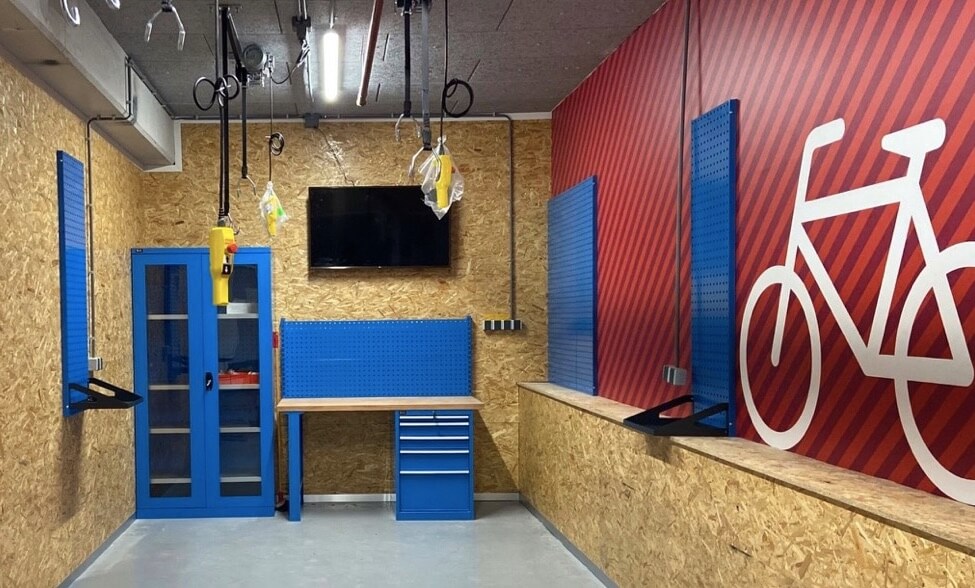 A small workshop lined with OSB panels, red wall and blue storage units