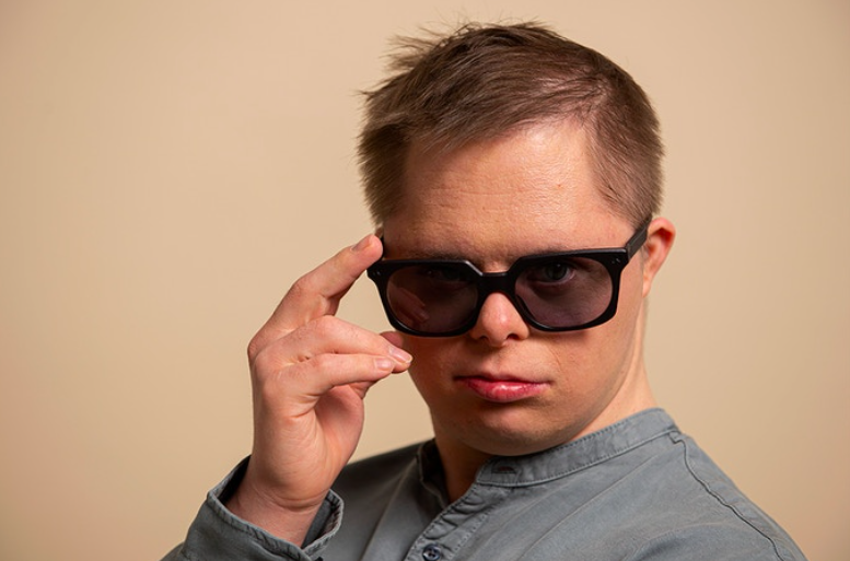 A man with Down syndrome sporting a pair of black sunglasses