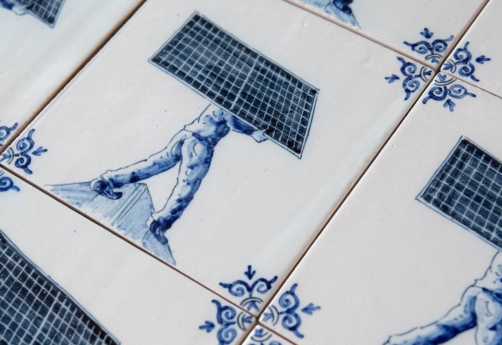 Traditional blue-and-white ceramic tiles showing an installer carrying a solar panel