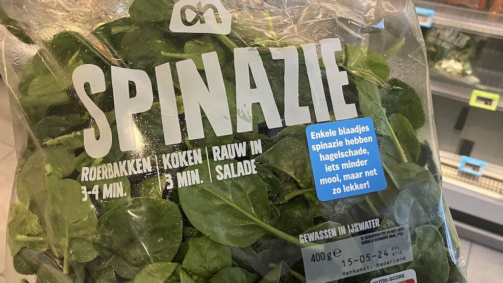 Bag of spinach with a label explaining some leaves suffered hail damage 