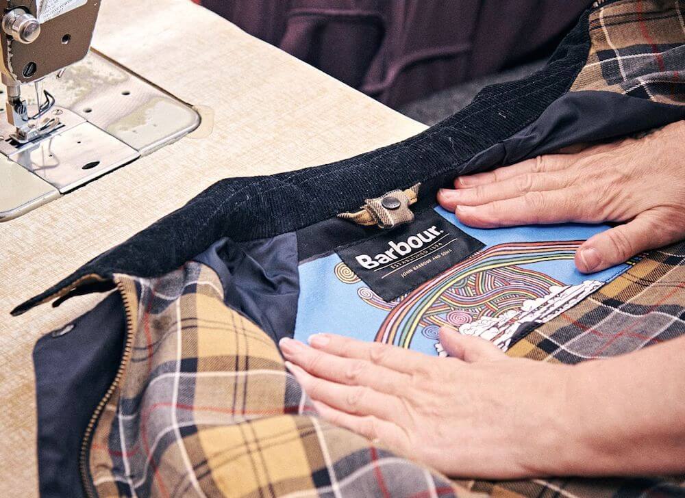 Hands smoothing Glastonbury-themed fabric inside a Barbour jacket