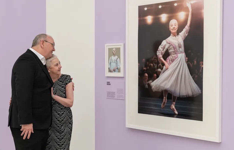 A happy, older couple looking at a framed photo of her dancing on stage