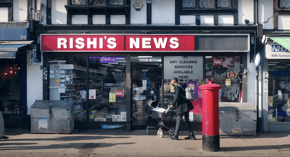 Man with a baby carriage entering a convenience store called Rishi's News