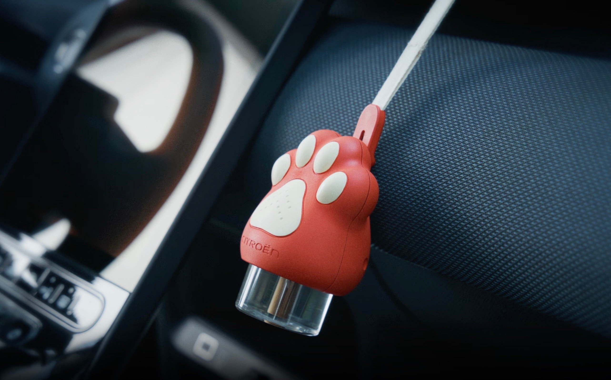 A Citroën-branded Calm Diffuser shaped like a reddish animal paw with white pads, shown in a dark car interior 