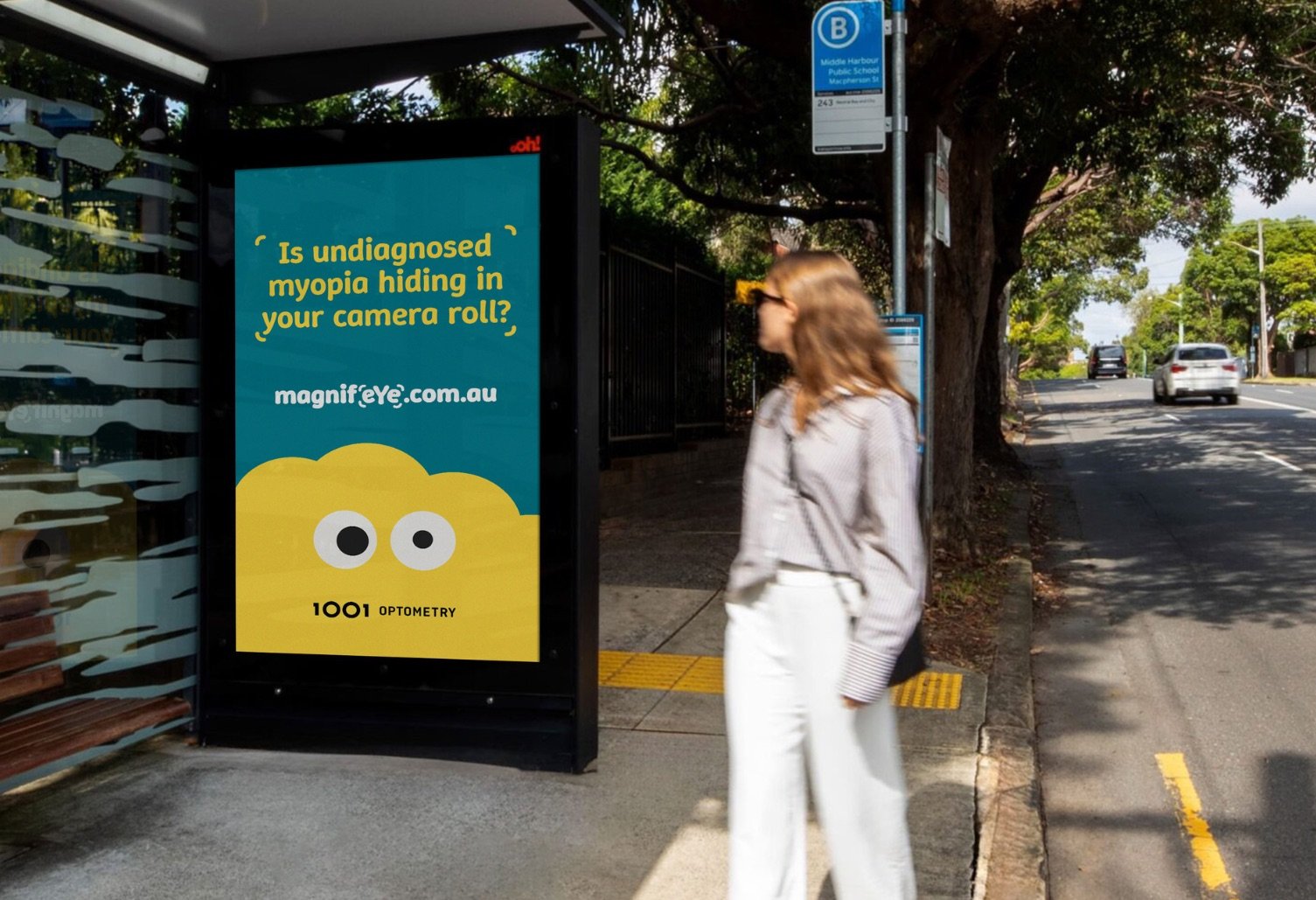 A woman walks past a bus shelter ad. The backlit poster features a teal and yellow design with cartoon eyes and the text 
