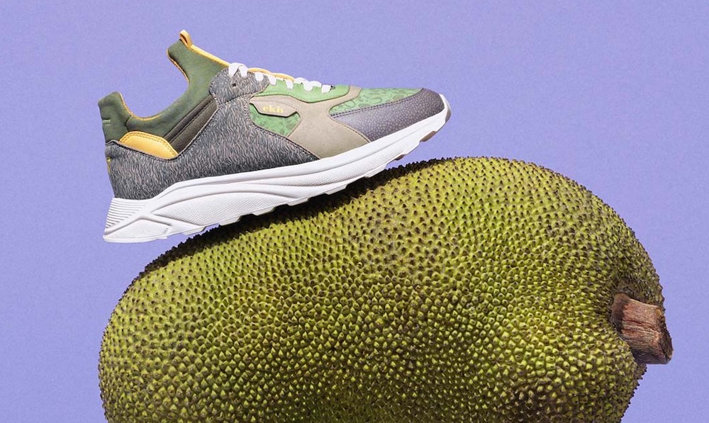 A gray, green and yellow sneaker balanced on a huge jackfruit