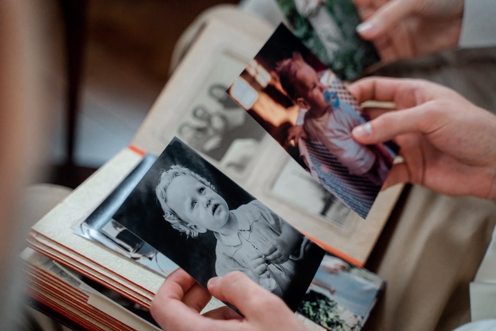 Two hands holding two old photos of young children