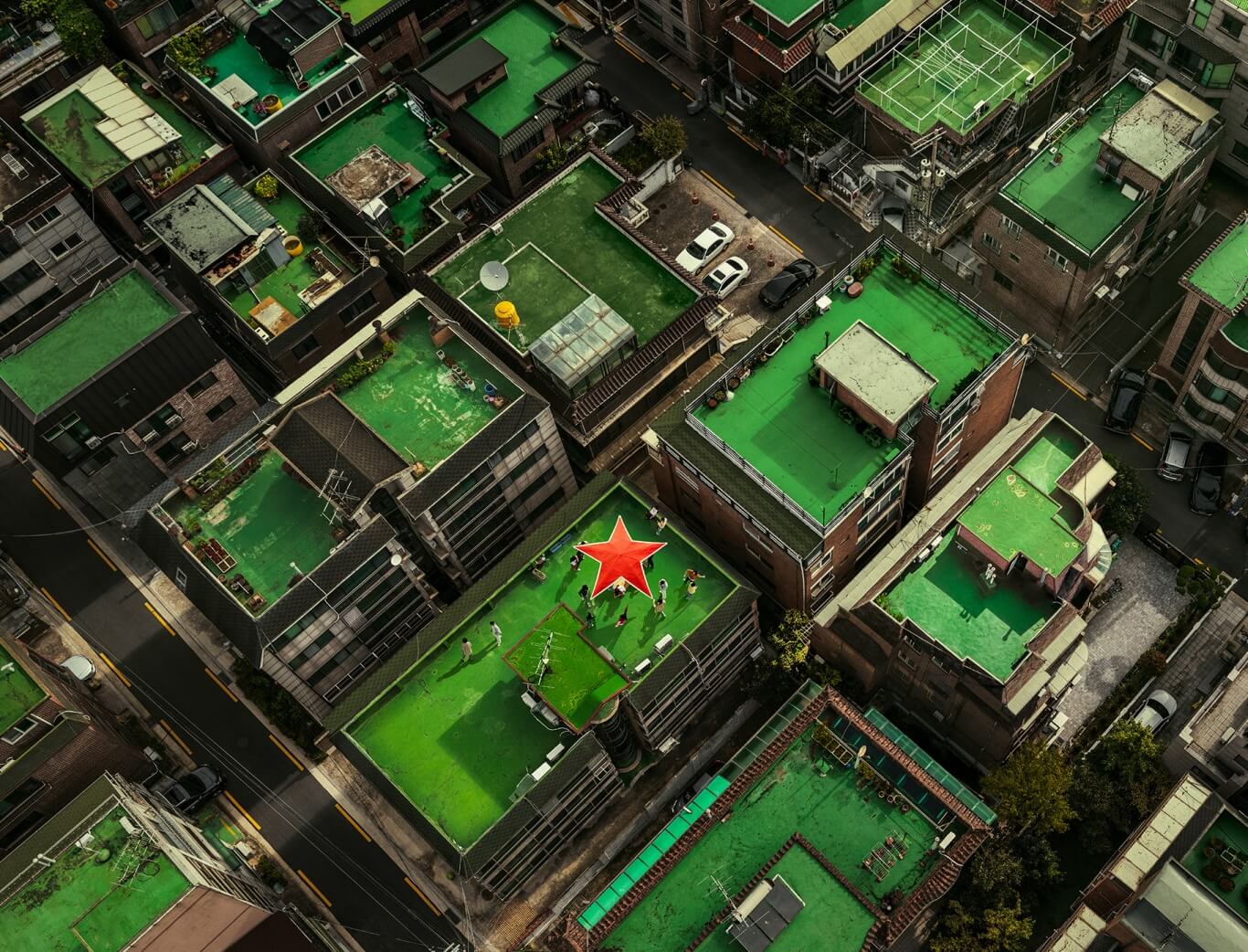 Aerial view of Seoul rooftops, mostly painted green, with one rooftop transformed into a social hub marked by Heineken’s trademark red star 