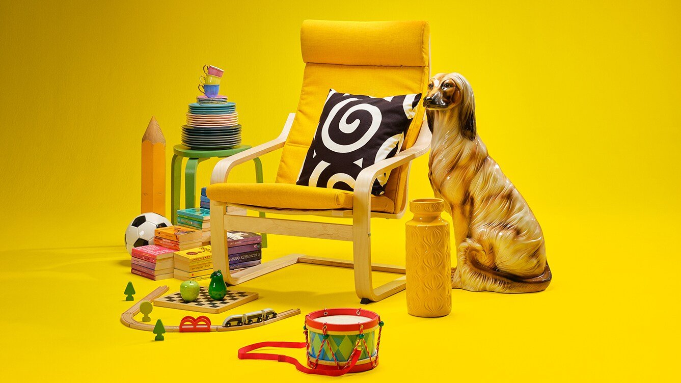 Against a yellow background, an IKEA chair and various toys and other objects 