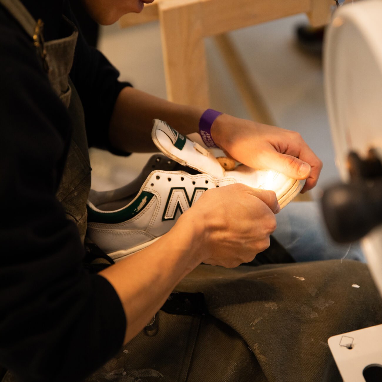 Student repairing a white sneaker under a work light 
