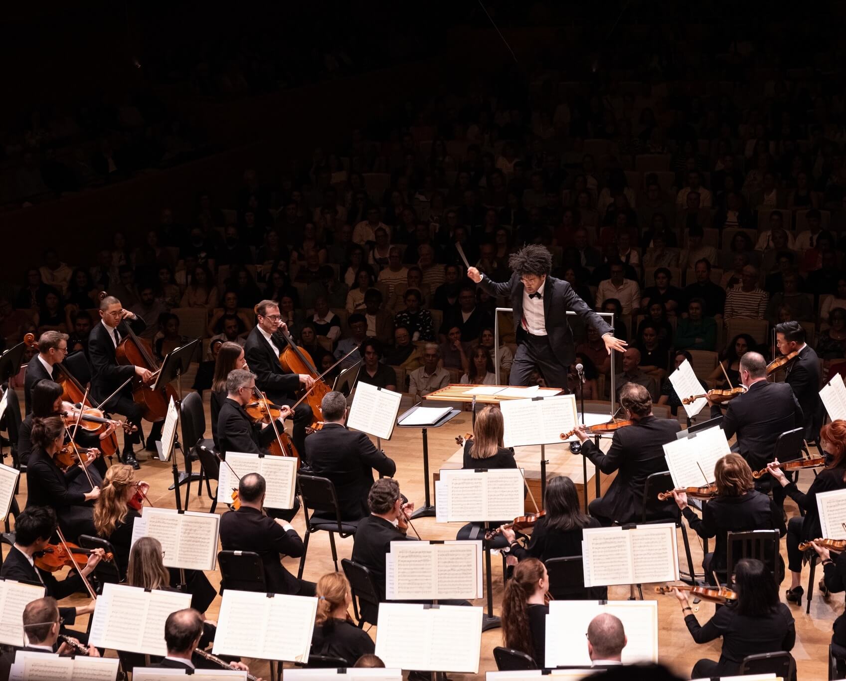 Conductor Rafael Payare leads the Orchestre symphonique de Montréal, with musicians playing string and wind instruments on stage before a full concert hall audience 