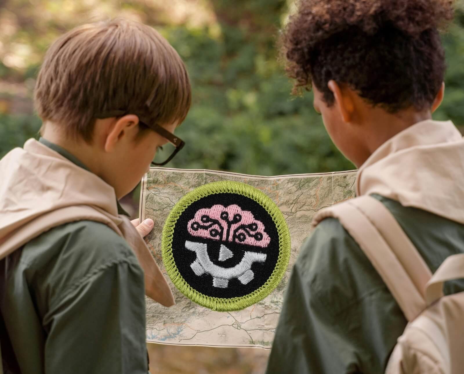 Two Scouts in uniform examine a map together outdoors, with an AI merit badge prominently displayed 