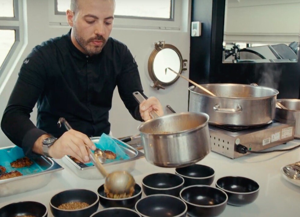 A chef ladles a thick soup into black bowls 