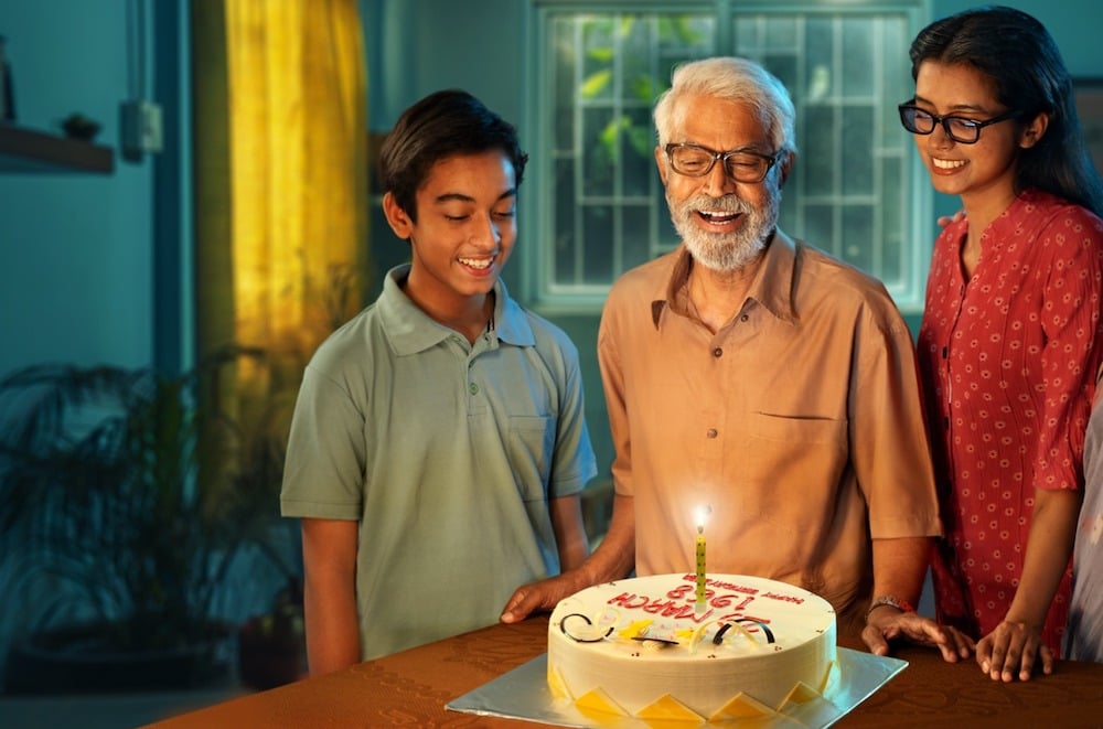 Surrounded by his children, is father is about to blow out a candle on his birthday cake