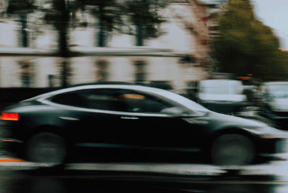 Blurry photo of a black Tesla driving through rainy London