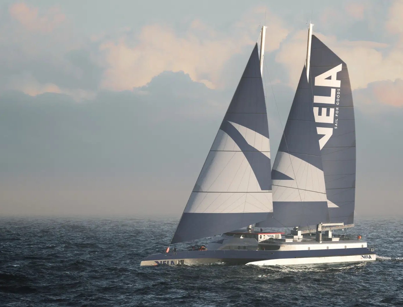 A large, modern trimaran with two tall blue-and-white sails moves across the ocean under a cloudy sky 